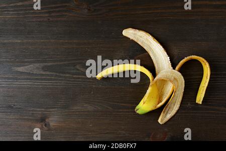 Peau de banane isolée sur le fond en bois pour le concept de LES AVANTAGES DE LA PEAU DE BANANE Banque D'Images