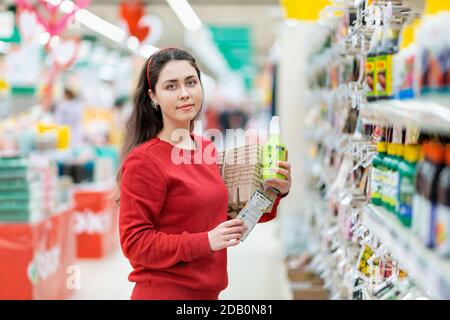 Une jeune femme caucasienne pose avec des pots de semis, des graines de fleurs et des engrais végétaux dans ses mains. Gros plan. Concept de jardinage et de préparation pour t Banque D'Images