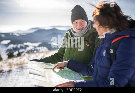 Les randonneurs en couple senior utilisent la carte dans la nature enneigée de l'hiver. Banque D'Images