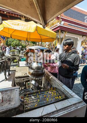 Bangkok, Thaïlande - 7 décembre 2019: Les gens qui paient le respect avec des bâtons d'Encens sur le pot de Joss-stick dans le Temple du Bouddha d'Émeraude (Wat Phra Kaew) Banque D'Images