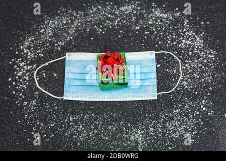 Masque de protection médical avec petite boîte cadeau. Cadeaux de Noël en quarantaine. Concept d'auto-isolement des fêtes et de pandémie de coronavirus Banque D'Images