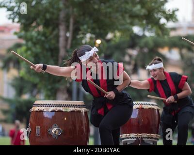 Fille jouant des tambours de la tradition musicale japonaise lors d'un événement public en plein air. Banque D'Images