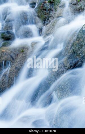 Gros plan d'eau douce de la cascade tropicale qui coule sur le calcaire en saison de pluie, eau pure qui coule sur des couches de mur de calcaire. Exposition longue. Banque D'Images