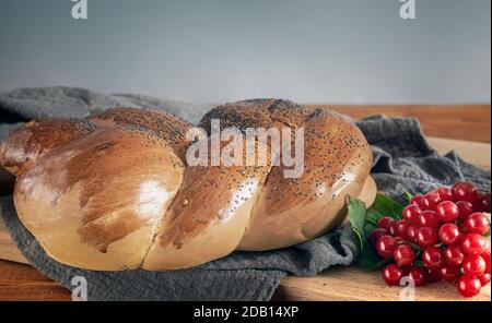 Un pain blanc à croûte croustillante, parsemé de graines de pavot et de baies de viburnum sur la table. Vue de face, où vous souhaitez copier. Banque D'Images