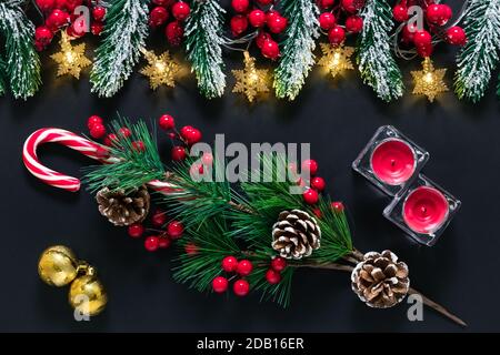 Décorations d'arbres de Noël sur fond sombre. Ambiance d'hiver, baie holly, cône de pin, branche d'épinette avec neige sur tableau noir. Carte postale de fête avec éclat Banque D'Images