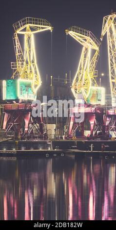 Grues de port illuminées sur l'île de Lasztonia à Szczecin lors d'une nuit brumeuse, en Pologne. Banque D'Images