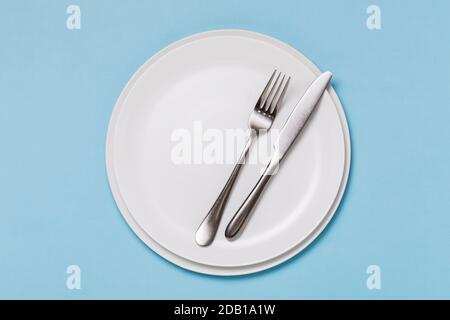 Videz l'assiette blanche et les couverts sur un fond bleu, vue du dessus. La nourriture Banque D'Images