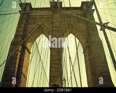 Détail d'une tour néo-gothique calcaire avec les câbles suspendus du pont de Brooklyn, célèbre monument de New York sur la rivière East. Banque D'Images