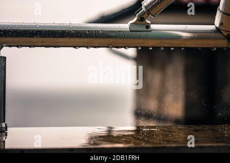 Gouttes de pluie sur la balustrade métallique du balcon de près après la pluie, vue de la fenêtre. Banque D'Images