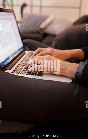 Femme travaillant les mains avec un ordinateur portable assis sur le canapé Banque D'Images