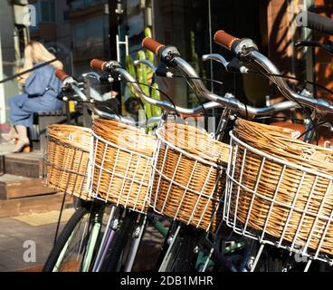 Vélos à l'ancienne avec panier en osier devant le magasin de vélos de tel Aviv, Israël. À l'arrière-plan jeune blonde élégante femme d'affaires assis à s. Banque D'Images