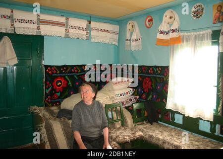 Maramures, Roumanie. Intérieur d'une maison ancienne, décoration traditionnelle faite à la main. Tapis tissé sur le mur et couvertures en laine sur le lit et le banc. Banque D'Images