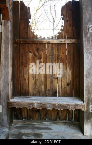 Maramures, Roumanie. Petit banc près d'une porte en bois traditionnelle. Banque D'Images