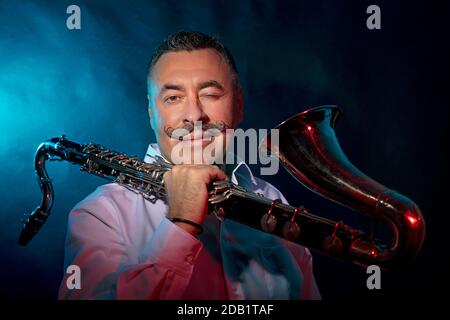 Homme avec un saxophone dans ses mains, photo dans le studio arrière-plan sombre. Photo de haute qualité Banque D'Images