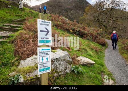 Pandémie de coronavirus Covid-19 signe bilingue avertissement garder à l'écart maintenir la distance sociale en anglais et Cadwch ar wahan en gallois sur un sentier. Pays de Galles Banque D'Images