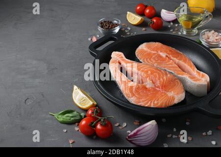 Steaks de saumon frais crus dans une poêle et ingrédients sur fond sombre. Copier l'espace Banque D'Images