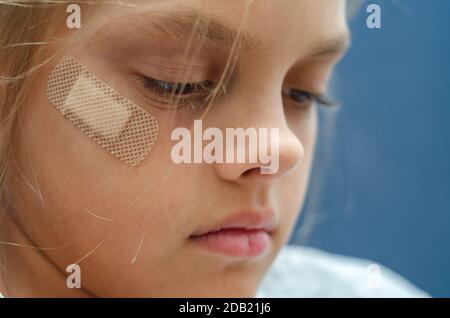 Sur le visage de la fille est collé Band-Aid, gros plan Banque D'Images