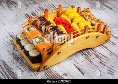 Un excellent ensemble de sushis avec une variété de rôles sur le plateau en bois d'origine, sur un fond gris. Restaurant servant des plats japonais. Banque D'Images