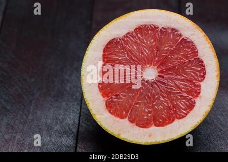 Pamplemousse tranché sur fond de bois d'acajou. Banque D'Images