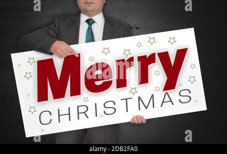 L'affiche Joyeux de Noël est tenue par l'homme d'affaires. Banque D'Images