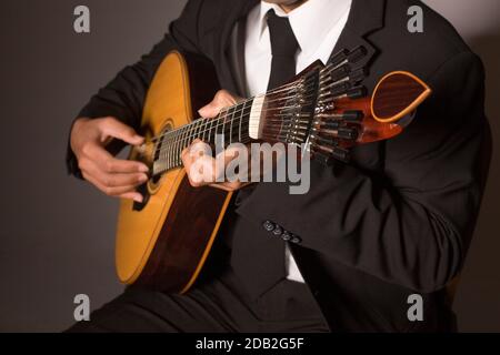 Gros plan d'un homme avec ses doigts sur les frettes d'une guitare portugaise Banque D'Images