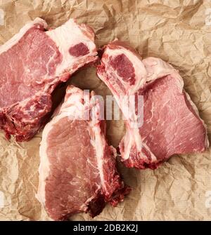 tranches de porc juteux cru de viande sur la côte, la nourriture se trouve sur du papier parchemin brun, vue de dessus Banque D'Images