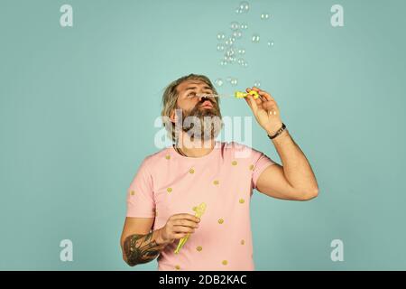 homme avec souffleur à bulles. happy hipster d'humeur ludique. Tombez dans l'enfance. Se sentir enfantin et enfantin. Vrai bonheur. Homme mûr soufflant des bulles de savon. Rester insouciant à tout âge. Banque D'Images