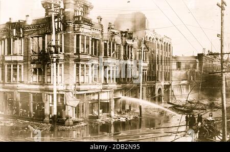 Bloc de bâtiments brûlés à San Francisco après le tremblement de terre de 1906 avec un camion d'incendie qui vaporise de l'eau sur eux. Banque D'Images