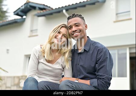 Heureux couple de course mixte assis devant leur nouveau accueil Banque D'Images