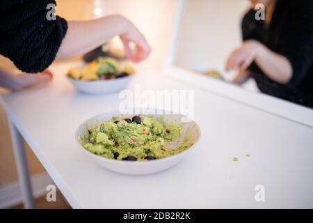 Bol de sauce guacamole aux olives sur une table blanche Banque D'Images
