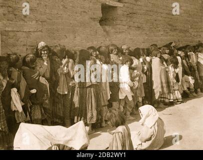 Ligne d'Apache hommes, femmes, et enfants à l'extérieur de l'agence bâtiment le jour de l'émission, San Carlos, Arizona. Banque D'Images