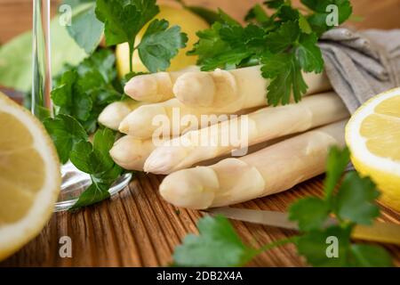 Asperges blanches sur une table rustique en bois, en linge de maison avec persil et citron. Gros plan avec une courte profondeur de mise au point. Concept de base pour la cuisine et Banque D'Images