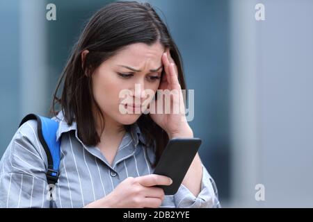 Un étudiant inquiet vérifie le message du smartphone en marchant dans la rue Banque D'Images