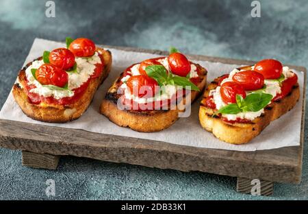 Bruschettas italiens avec mozzarella, riccotta, tomates cuites et basilic Banque D'Images