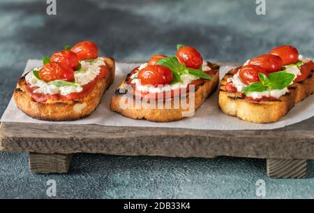 Bruschettas italiens avec mozzarella, riccotta, tomates cuites et basilic Banque D'Images