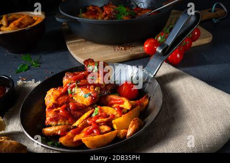 Ailes de poulet rustiques au miel avec quartiers de pommes de terre Banque D'Images