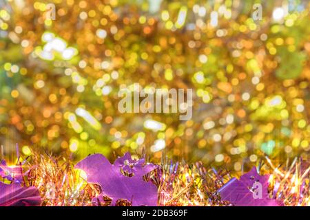 La texture d'arrière-plan flou d'or plein de petites guirlandes décorées avec des visages souriants des chauves-souris violet en premier plan pour célébrer l'halloween. Banque D'Images