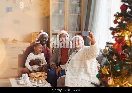 Portrait d'une grande famille afro-américaine heureuse prenant toutes des photos de selfie Porter des chapeaux de père Noël tout en appréciant Noël à la maison ensemble Banque D'Images