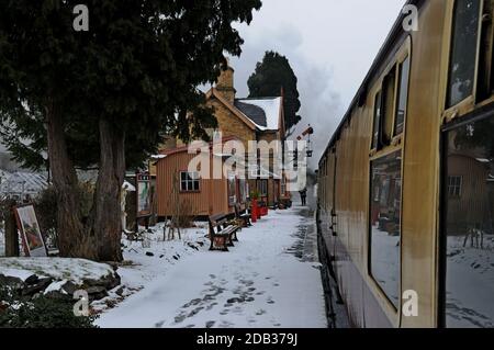 La station Master observe un train à vapeur au départ de la gare de Hampton Loade dans la neige, Severn Valley Railway, Shropshire Banque D'Images