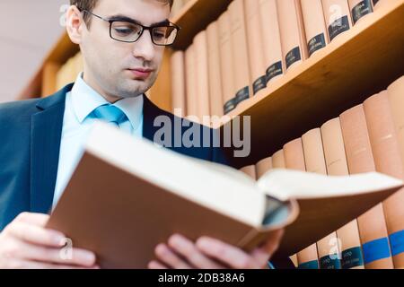 Avocat dans son bureau lisant des précédents dans des livres épais pensant à un cas Banque D'Images