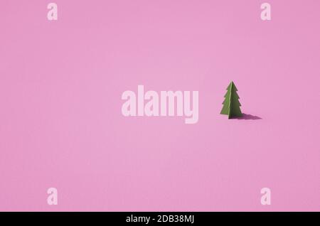 Maquette d'un seul arbre de conifères en 3D vert sur une surface rose rétro. Modèle en plastique de l'arbre sur la surface texturée. Arrière-plan sur le thème de Noël. Banque D'Images