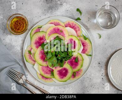 salade de detox de radis pastèques et d'arugula dans une assiette. Nourriture saine maison. Fond en béton léger ou en pierre. Vue sur le dessus Banque D'Images