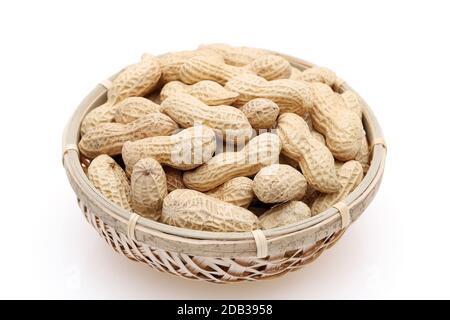 Arachides biologiques en coquille dans un panier de bambou sur fond blanc Banque D'Images