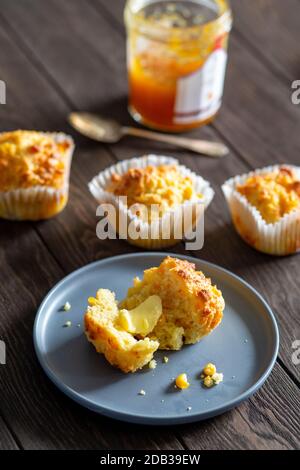 Muffins au pain de maïs avec beurre et confiture et une cuillère sur une assiette bleue sur un fond en bois - FOOPPIX Banque D'Images