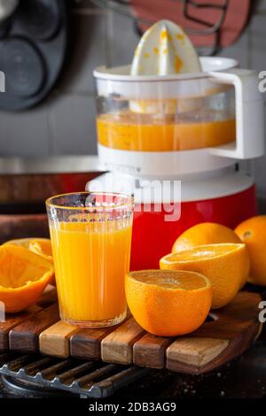 Centrifugeuse en plastique rouge et blanc à l'ancienne avec des oranges coupées en deux pour le jus et un verre de jus d'orange fraîchement pressé - FOOPPIX Banque D'Images