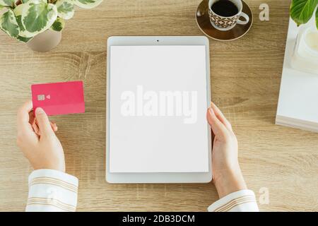 Tablette verticale avec une femme tenant une carte de crédit dans sa maison. Écran vide pour insérer le modèle. Concept de commerce électronique Banque D'Images