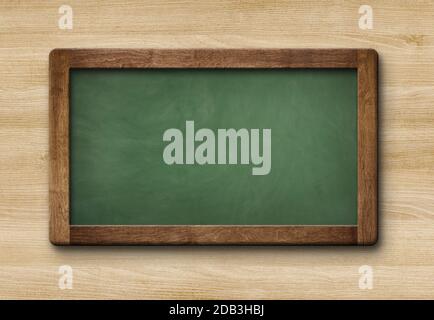 Petit tableau noir blanc vert ardoise avec cadre en bois isolé sur fond en bois Banque D'Images