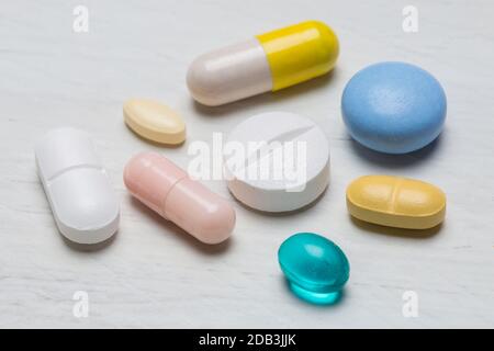 Colorful pills on white wooden background close up. Stock Photo