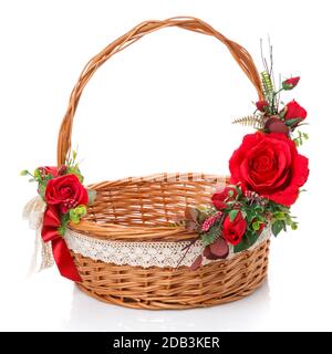 Panier en vigne naturel décoré avec poignée haute. Décor de roses rouges et ruban en dentelle sur fond blanc. Vue latérale Banque D'Images