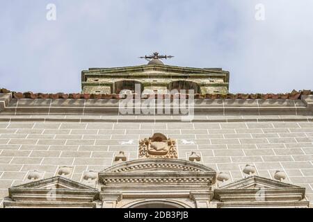 Clocher d'une église avec une croix métallique sur le dessus et détails sculptés en pierre sur la façade, à l'ouest de l'Espagne, à Serradilla (Caceres) Banque D'Images